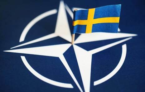En Sverigeflagga placerad mitt i NATO-flaggan.
